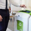 Man in an office throwing plastic bottle into recycling bin