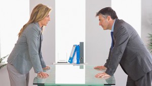 Two irritated businesspeople arguing on each side of a desk