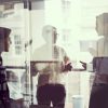 A photo of business people discussing in meeting room. Businesswoman talking with male colleagues. They are in modern glass office.