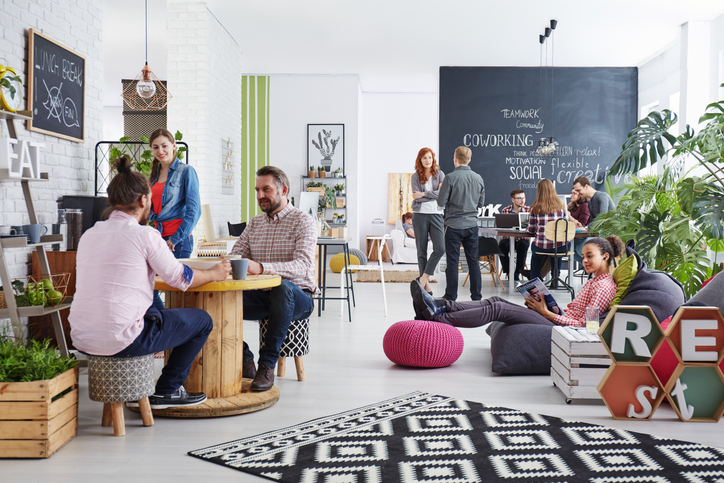 A group of coworkers gathering for a meeting in a contemporary office conference room.